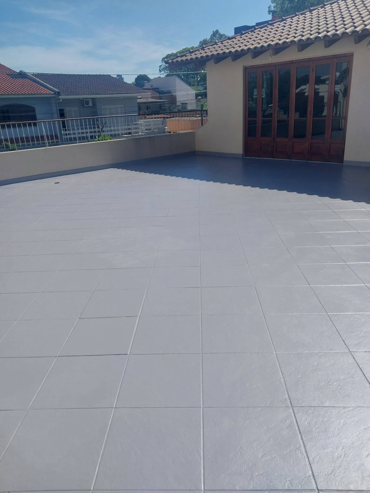 Piso amplo de terraço impermeabilizado em tom cinza-claro com acabamento uniforme, vista de telhados vizinhos, fotografia realista